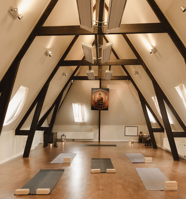 De Shala: yogazaal met matten onder de houten spanten